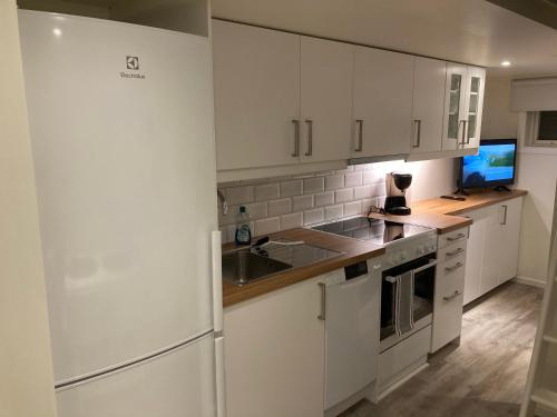 a kitchen with white cabinets and a sink and a refrigerator at Smeakallesbod in Tvååker