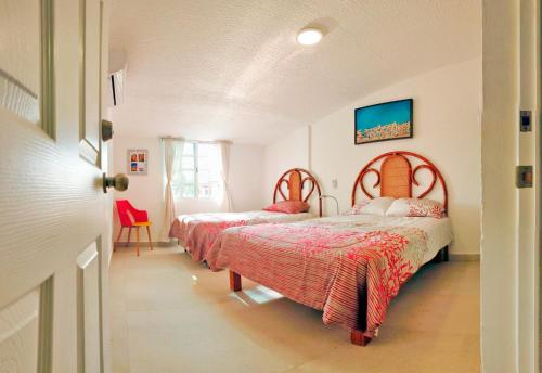 una camera con due letti con coperte rosse di HominngBird Acapulco ad Acapulco