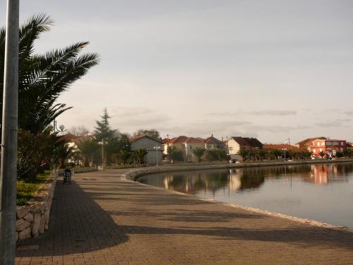 a sidewalk next to a river with houses and a street at Apartmani Vera in Bibinje