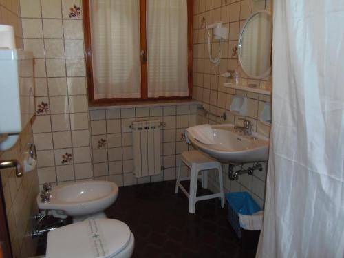 uma casa de banho com 2 lavatórios, um WC e um espelho. em Hotel Italia em Moneglia