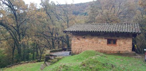 a small stone building on a hill in a forest at Cabaña Castañarejo in Candeleda