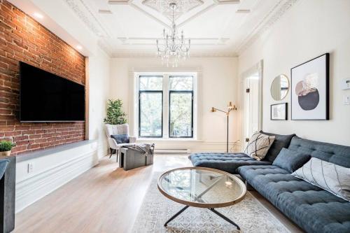 a living room with a blue couch and a brick wall at Montreal Styled 2 BR Apartment on St-Denis Street in Montréal