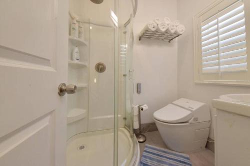 a white bathroom with a shower and a toilet at 1000#4 Modern Beach Home, Steps from Sand w/AC! in Newport Beach