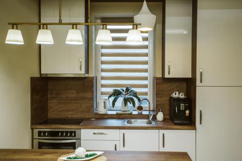 a kitchen with white cabinets and a sink at Vively Lux Apartment - Central & Spacious with Balcony and free WiFi in Subotica
