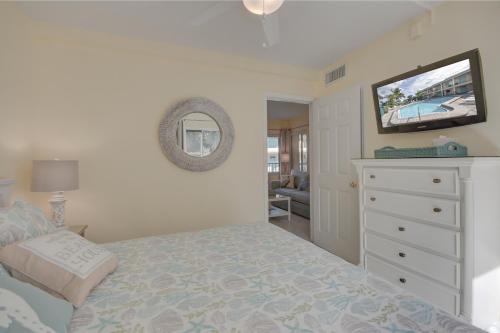 a bedroom with a bed and a dresser with a tv at Five Palms Vacation Rentals- Daily - Weekly - Monthly in Clearwater Beach