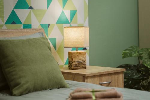 a bedroom with a bed and a table with a lamp at Vively Lux Apartment - Central & Spacious with Balcony and free WiFi in Subotica