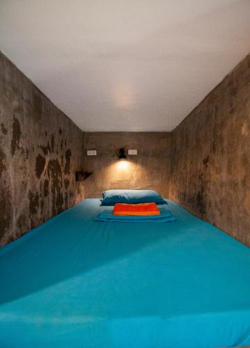 a room with a large blue bed with blue sheets at Sunlit Hostel in General Luna