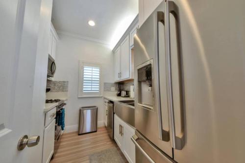 a kitchen with white cabinets and a stainless steel refrigerator at 1000#5 Premier Modern Home w View, Parking, and AC in Newport Beach