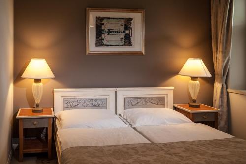 ein Schlafzimmer mit einem Bett und zwei Lampen auf Tischen in der Unterkunft Páskom Cottage in Lajoskomárom
