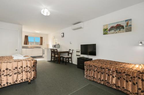 a hotel room with two beds and a television at Arcadia Motel in Christchurch