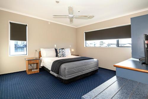 a hotel room with a bed and two windows at Bay City Motor Lodge in Timaru