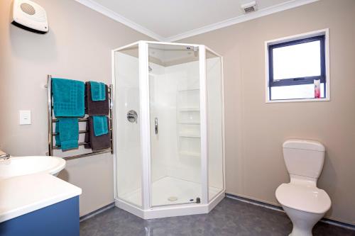 a bathroom with a shower with a toilet and a sink at Bay City Motor Lodge in Timaru