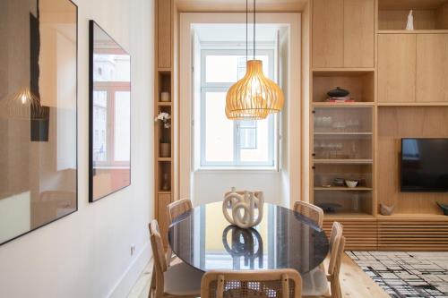 uma sala de jantar com uma mesa de vidro e um lustre em FLH Praça Comércio Tropical Flat em Lisboa