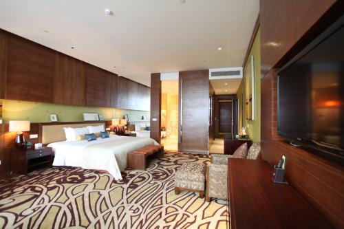 a hotel room with a bed and a flat screen tv at HJ International Hotel in Dongguan
