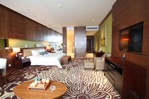 a hotel room with a bed and a flat screen tv at HJ International Hotel in Dongguan