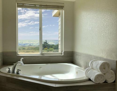 a bath tub in a bathroom with a window at SureStay Plus Hotel by Best Western Gold Beach in Gold Beach