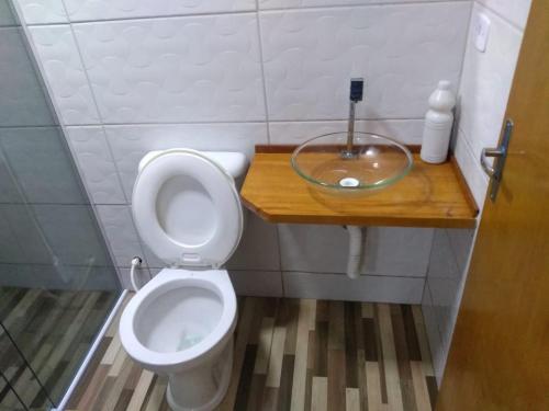 uma casa de banho com WC e uma taça de vidro no balcão em Kitnet contêiner climatizada em Ubatuba