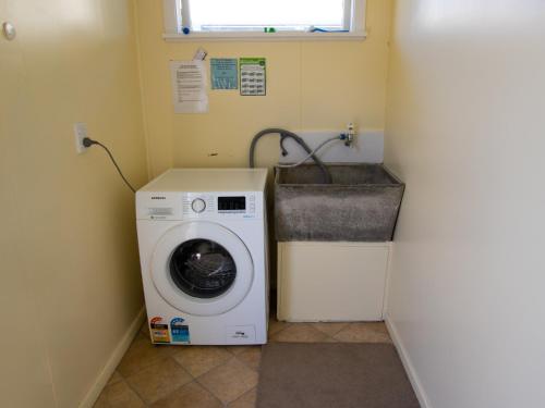 a laundry room with a washing machine and a sink at Beach Tata - Golden Bay Bach Tata Beach in Tarakohe