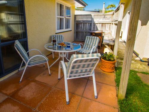 a patio with a table and chairs on a porch at Beach Tata - Golden Bay Bach Tata Beach in Tarakohe