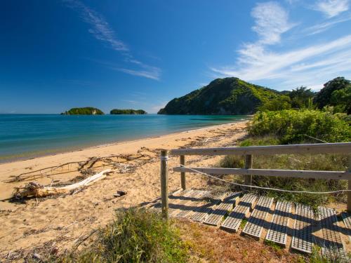 a view of a beach with a wooden fence at Beach Tata - Golden Bay Bach Tata Beach in Tarakohe