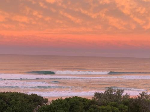 a sunset over the ocean with waves at Capricorn One Beachside Holiday Apartments - Official in Gold Coast