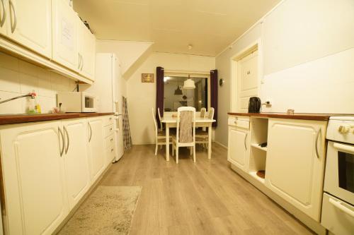 a kitchen with white cabinets and a dining table at Hage Rooms in Tromsø