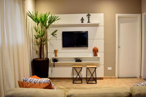 uma sala de estar com um sofá e uma televisão na parede em O Recanto Pousada em Serra Negra