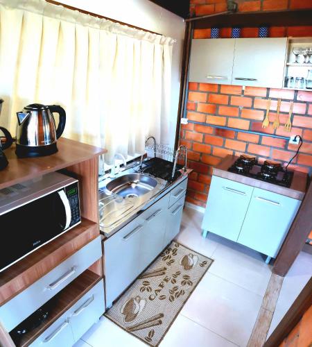 a small kitchen with a sink and a microwave at Pousada Doce Mar in Guarda do Embaú