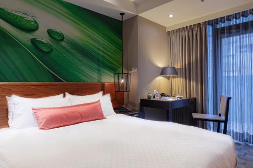 a bedroom with a bed and a desk and a green wall at Pacific Business Hotel in Taipei