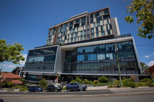 a large building with cars parked in front of it at Essence Suites Taringa in Brisbane
