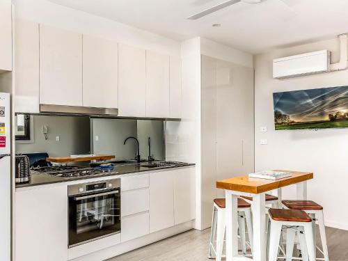 a kitchen with white cabinets and a wooden table at The View at Seascape in Gerringong