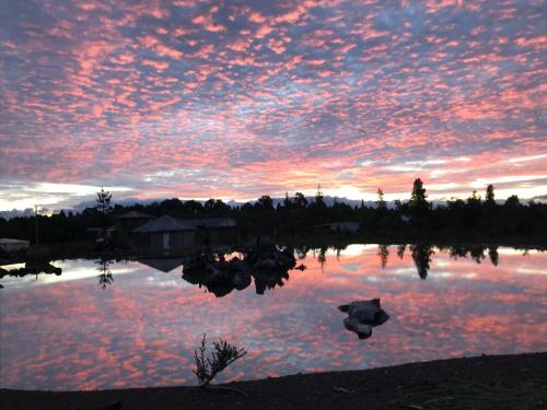 a sunset over a lake with trees and houses at Parque la Pajarera in Puerto Varas