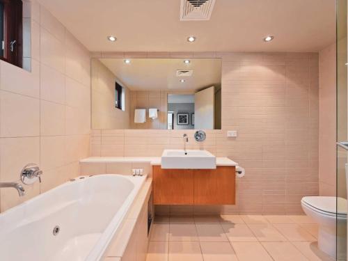 uma casa de banho com uma banheira, um lavatório e um WC. em Snow Stream 2 Bedroom and loft with gas fire balcony and garage parking em Thredbo