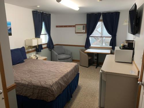 a hotel room with a bed and a desk and a chair at Peaks Lodge in Revelstoke