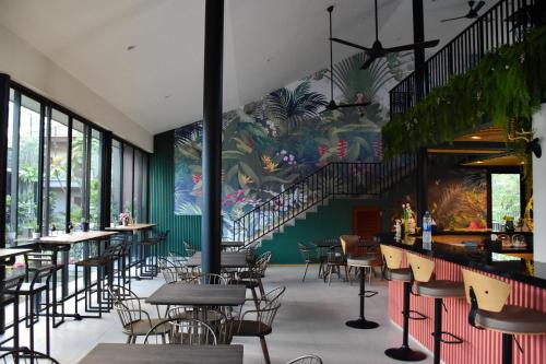 un restaurante con mesas y sillas y una escalera en JINGLE JUNGLE RESORT KHAOYAI en Mu Si