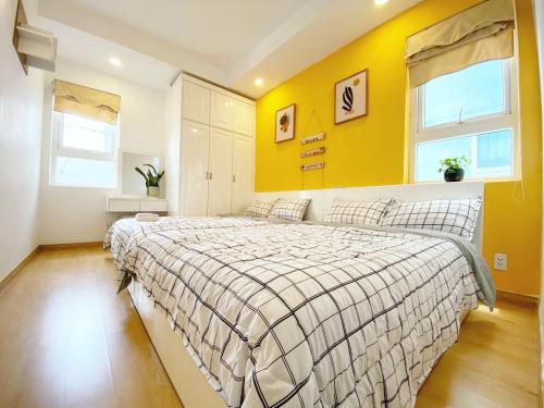 a bedroom with a bed with a yellow wall at Luxury Cookies Apartment Vung Tau Gold Sea Melody in Vung Tau