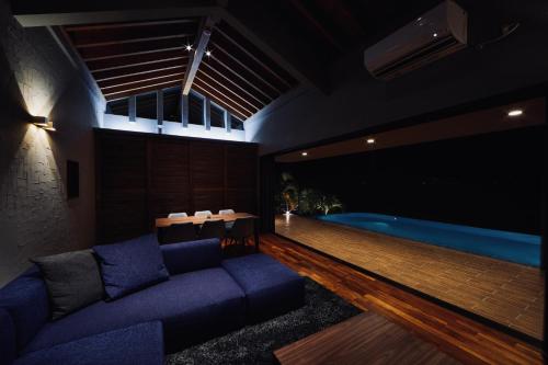 a living room with a couch and a swimming pool at relax kouri villa Rekrrr in Nakijin