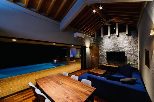 a living room with a table and a swimming pool at relax kouri villa Rekrrr in Nakijin