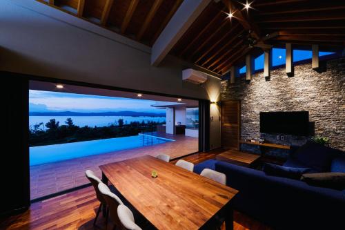 a living room with a table and a large window at relax kouri villa Rekrrr in Nakijin