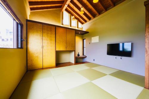 an empty room with a tv and a tiled floor at relax kouri villa Rekrrr in Nakijin
