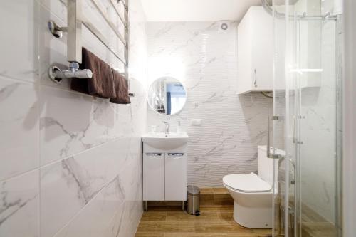 a white bathroom with a toilet and a sink at Pure Apartments in Lviv