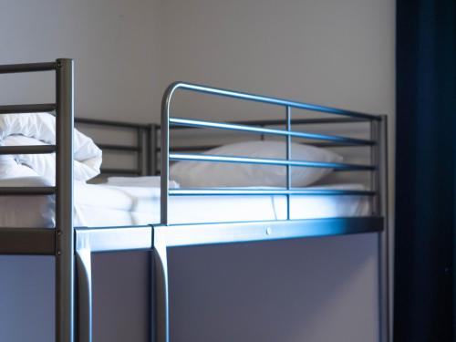 a metal bunk bed with white sheets and pillows at Björkbackens Karaktärshotell in Vimmerby