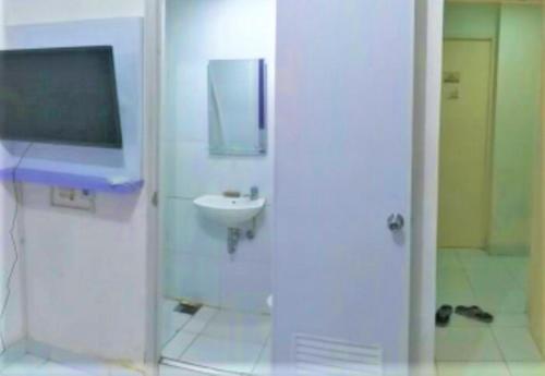a bathroom with a sink and a tv on the wall at Barata Hotel AR1 in Tangerang