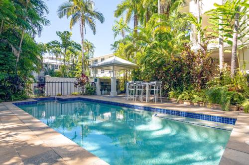 a swimming pool in front of a house with palm trees at Mandalay Luxury Beachfront Apartments in Port Douglas