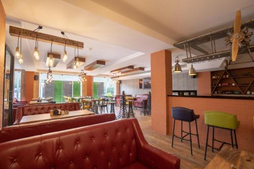 un restaurant avec des sièges en cuir rouge et un bar dans l'établissement Jenneys Residency, à Coimbatore