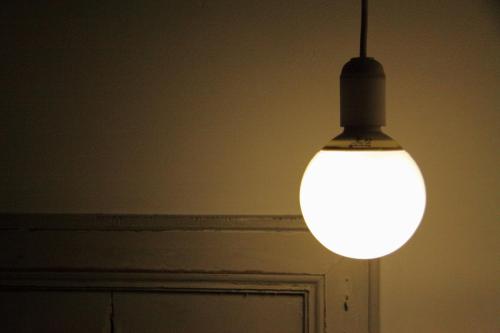 a light bulb hanging in a room with a door at Las Coles Apartasuites in Xàtiva