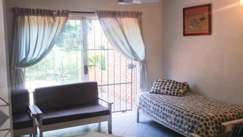 a bedroom with a bed and a chair and a window at Stokkiesdraai Holiday Apartments in St Lucia