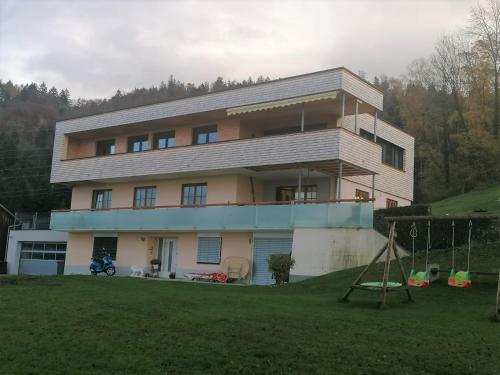 una grande casa con un parco giochi di fronte di Hausblick Matt, Lochau a Lochau