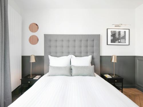 une chambre avec un grand lit blanc avec deux lampes dans l'établissement LivinParis - Luxury 2 Bedrooms Opera I, à Paris