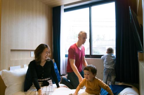 a family standing around a bed in a room at Sakura Cross Hotel Shinjuku East Annex in Tokyo